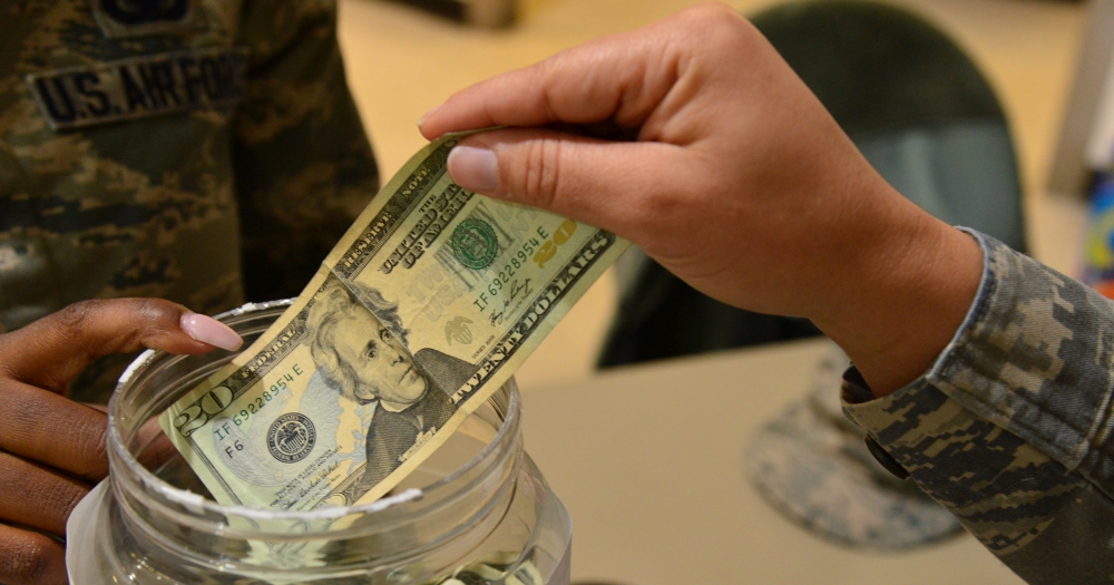 ofiara na tacę - jedna ręka wkłada banknot do słoika, zdjęcie: defense.gov, CC-0